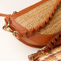 Straw handbag with brown leather accents on a white background
