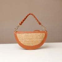 Half-circle handbag with straw texture and brown leather accents on a neutral background