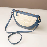 Blue handbag with a straw-like interior on a white surface
