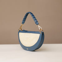 Blue handbag with braided handle on a beige background