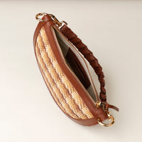 Brown handbag with a textured strap on a light beige background