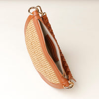 Brown leather and straw clutch bag on a light beige background