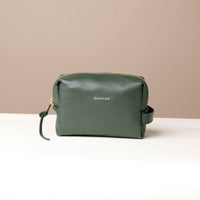 A green leather toiletry bag with a zipper closure and a small leather strap, displayed against a neutral background.