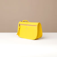 Yellow handbag on a white surface with a beige background