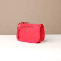 Red toiletry bag with a gold zipper on a beige background