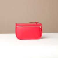 Red pouch with a gold zipper on a beige background