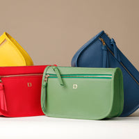 Four colorful handbags (yellow, red, green, blue) on a beige background