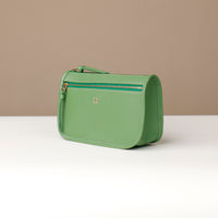 Green handbag on a white surface with a beige background