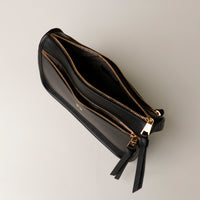 Black leather wallet with gold zipper on a light gray background