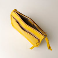 Yellow wallet with a strap on a light gray background