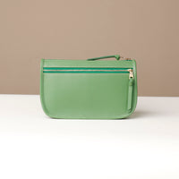 Green leather pouch with a gold zipper on a beige background