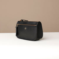Black handbag with a gold zipper on a beige background