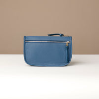 Blue leather pouch with a gold zipper on a beige background