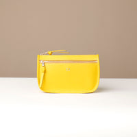 Yellow pouch with a brand logo on a beige background