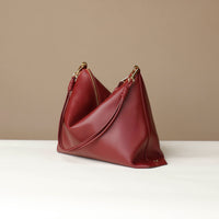 Red handbag with gold accents on a white surface and beige background