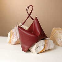 Red handbag on a textured surface with a neutral background