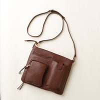 Brown leather handbag with a strap on a light beige background