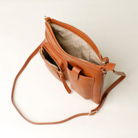 Brown leather handbag with a strap on a light beige background