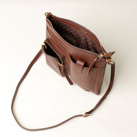 Brown leather handbag with gold accents on a light beige background