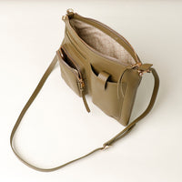 Green handbag with a strap on a light beige background