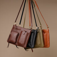Four leather handbags in different colors hanging against a beige background