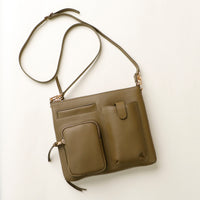 Green handbag with a detachable strap on a light beige background