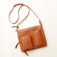 Brown leather handbag with a strap on a white background