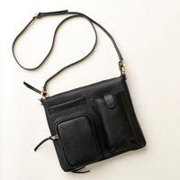 Black leather handbag with a strap on a light beige background