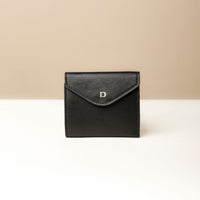 A black, compact, block-patterned leather wallet with a secure magnet snap closure and a small brand embossment on the front.