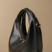 Close up view of black Soft Rounded Bag crescent leather top-handle handbag