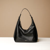 A black, hobo-style leather handbag with a slouchy silhouette and a minimalist design, displayed against a neutral background.