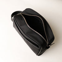 Open Black Fabricio leather toiletry bag with roomy interior and organized compartments, perfect for travel or everyday storage of essentials