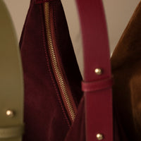 Close-up of burgundy Suede Mia Minimale – gold zipper, suede texture, and adjustable leather shoulder strap