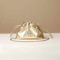 Gold handbag with chain detail on a beige background
