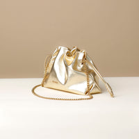 Gold metallic handbag with chain detail on a beige background
