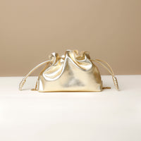 Gold handbag with a chain detail on a beige background