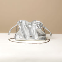 Silver drawstring bag with chain detail on a beige background
