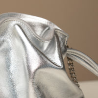 Close-up of a silver handbag with a chain detail on a beige background