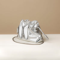 Silver metallic bag with chain detail on a beige background