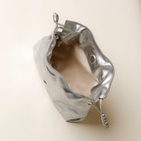 Silver metallic pouch with drawstring on a beige background