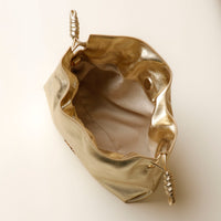 Gold metallic pouch with decorative handle on a white background