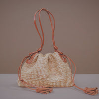 Woven handbag with drawstring on a neutral background