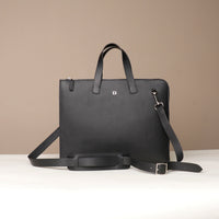 Black leather briefcase with shoulder strap on a beige background