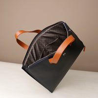 Blue leather bag with brown handles on a neutral background