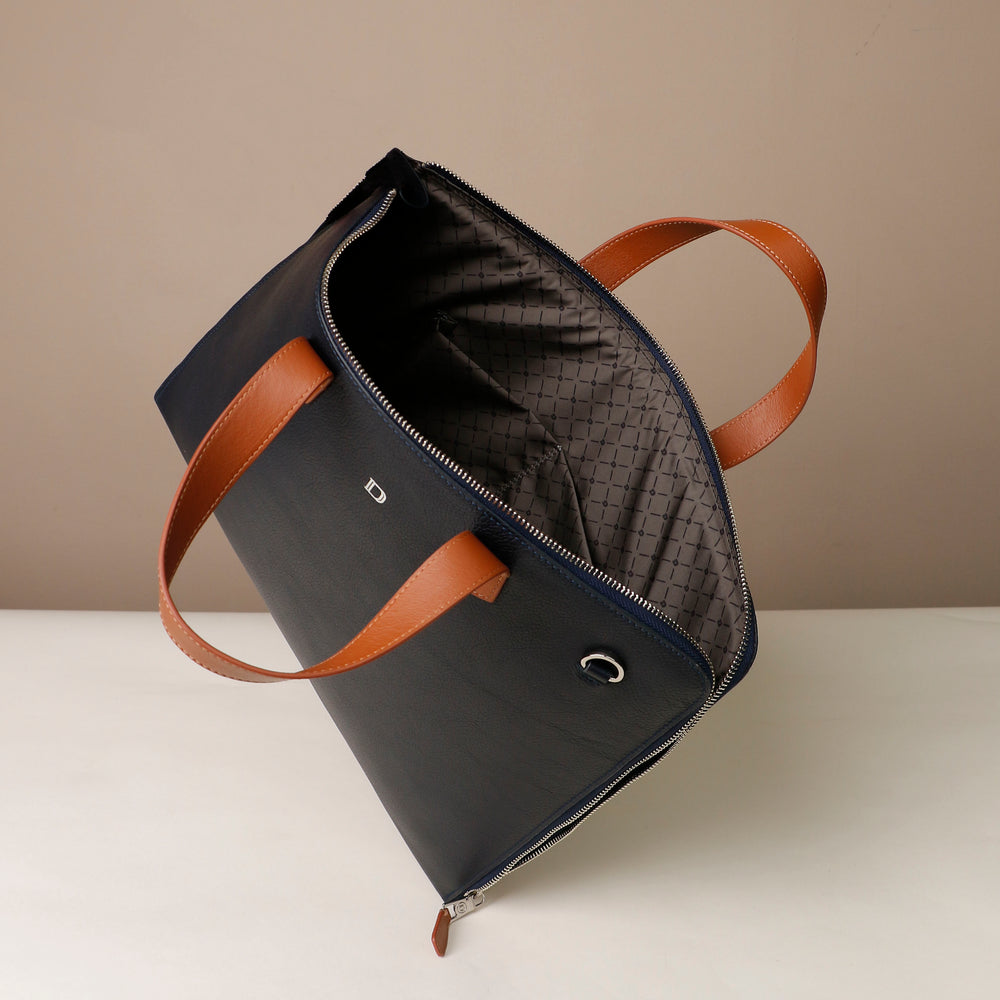 Black bag with brown straps on a white surface and beige background