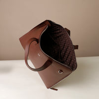 Brown leather handbag with quilted interior on a beige background
