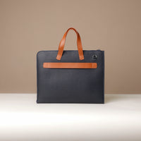 Blue bag with brown leather handle and trim on a beige background