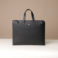 Black leather briefcase with a visible brand logo on a beige background