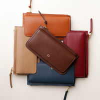 A collection of leather wallets in beige, brown, blue, and red colors, displayed stacked with the flap open on top.