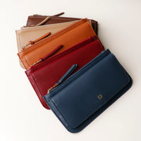 Stack of four leather pouches in different colors on a white background.
